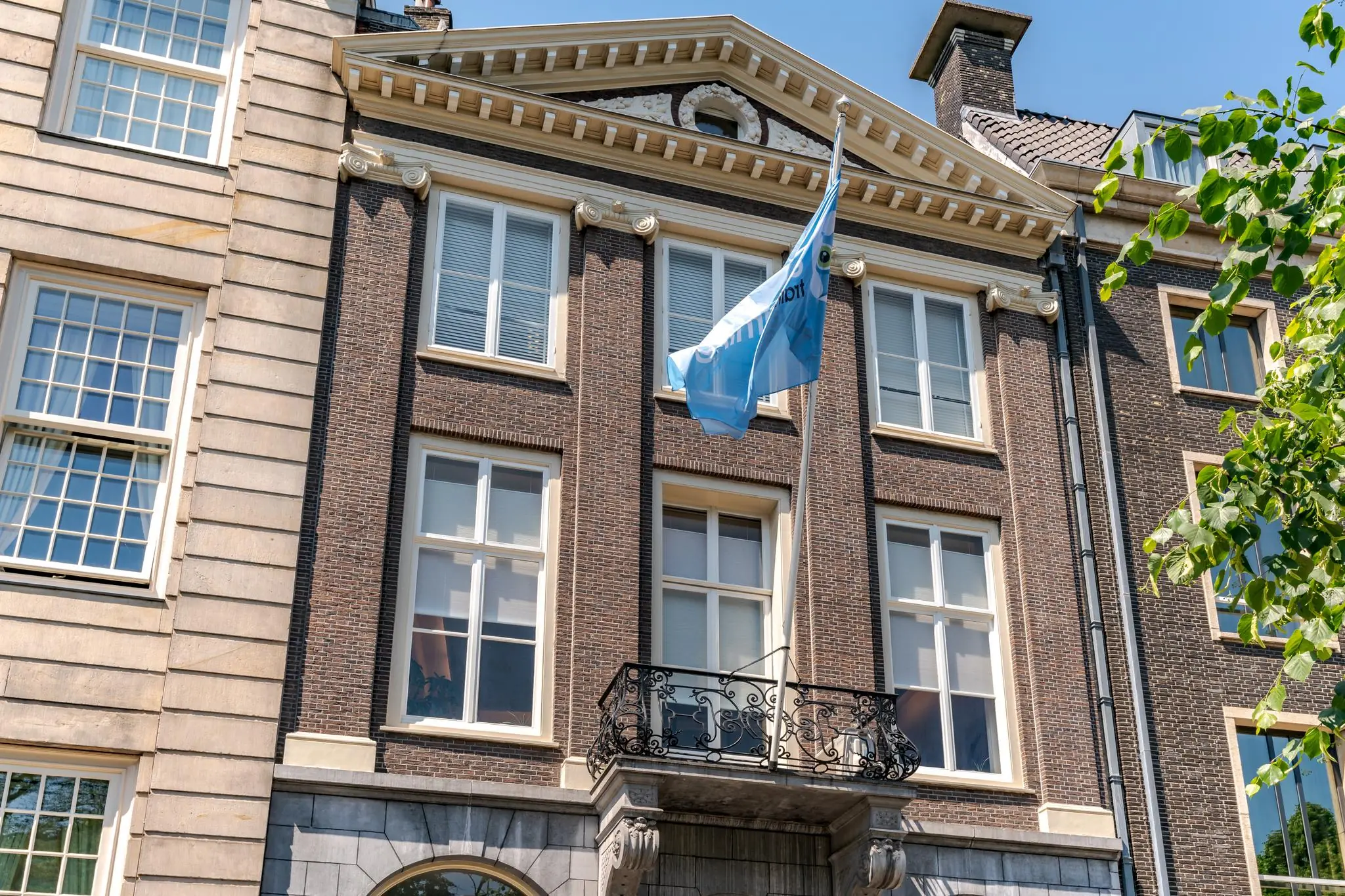 Voorgevel van een klassiek herenhuis aan de Lange Vijverberg met een blauwe vlag en smeedijzeren balkon.